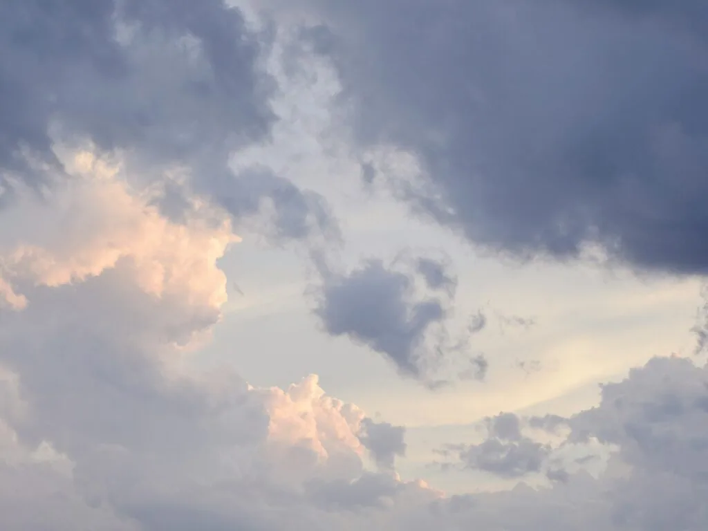 Dramatic sky with layered white and gray clouds illuminated by golden sunlight breaking through