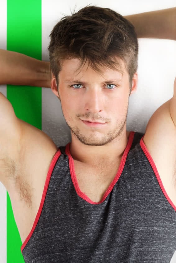 Young handsome male model with arms up in tank top against modern background with green stripe