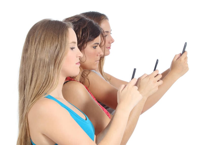 Group of teenager girls obsessed with the smart phone isolated on a white background
