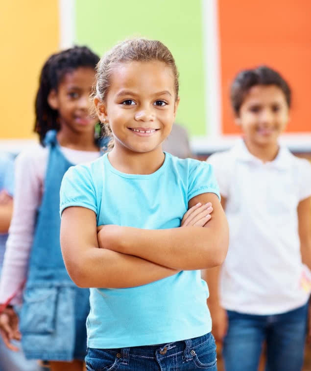 Confident little school girl with her classmates in the background