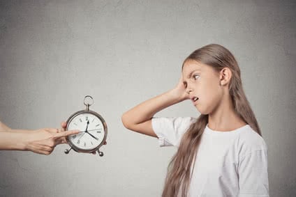 Kids time to go to bed. Portrait mom showing daughter clock that it is late. She doesn't like isolated grey wall background. Face expression emotions. Difficult parenting concept. Children's schedule