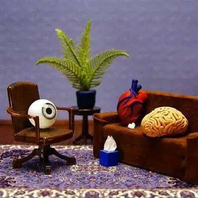 Miniature therapy scene with decorative brain and heart figures on brown furniture against purple background
