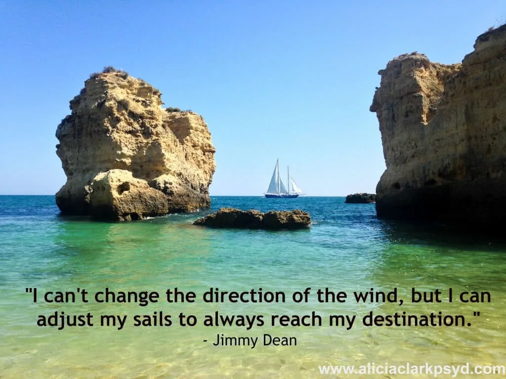 Sailboat anchored in turquoise waters between limestone rock formations with quote overlaid about adjusting sails to reach destinations.