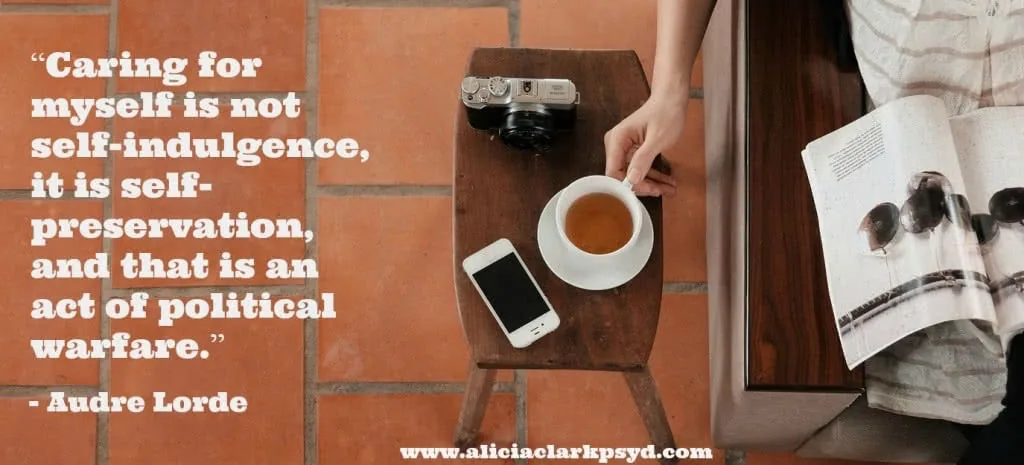Overhead view of wooden table with coffee cup, smartphone, vintage camera, and magazine next to Audre Lorde quote about self-care as political action