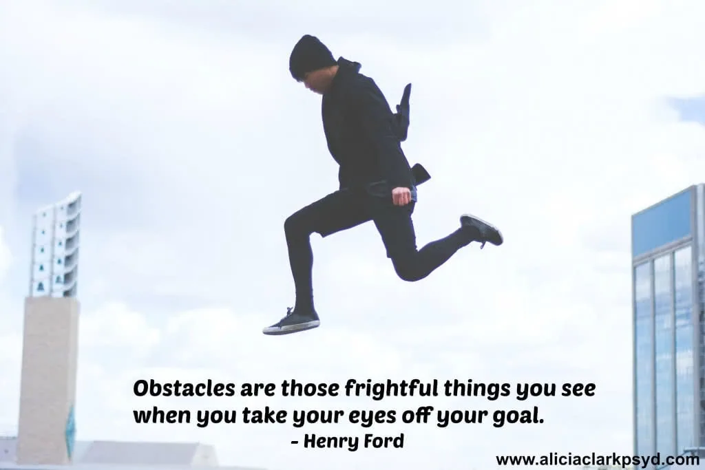 Person in black clothing jumping between two buildings with Henry Ford quote about obstacles below