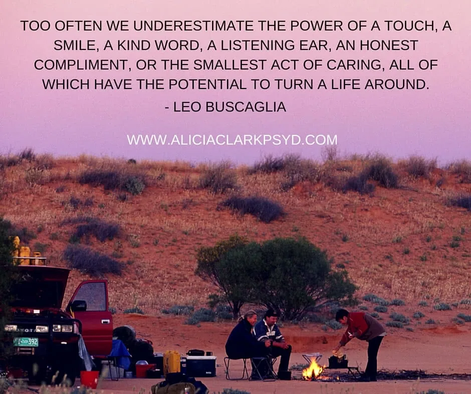 Group gathered around campfire at dusk in desert landscape with red truck and inspirational quote about kindness overlaid