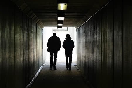 46903529 - two persons walk to the light at the end of the tunnel