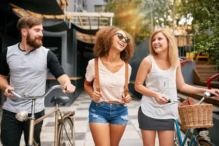 48982127 - happy young people walking down the city street with their bicycles and smiling. young man and women on road with their bikes.