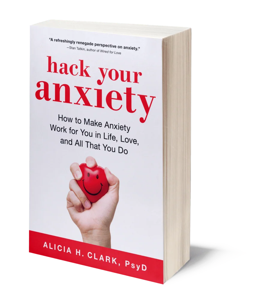 Paperback book titled 'hack your anxiety' with subtitle about making anxiety work for you in life, love, and all that you do, by Alicia H. Clark, PsyD, featuring a hand holding a red heart with a smiley face