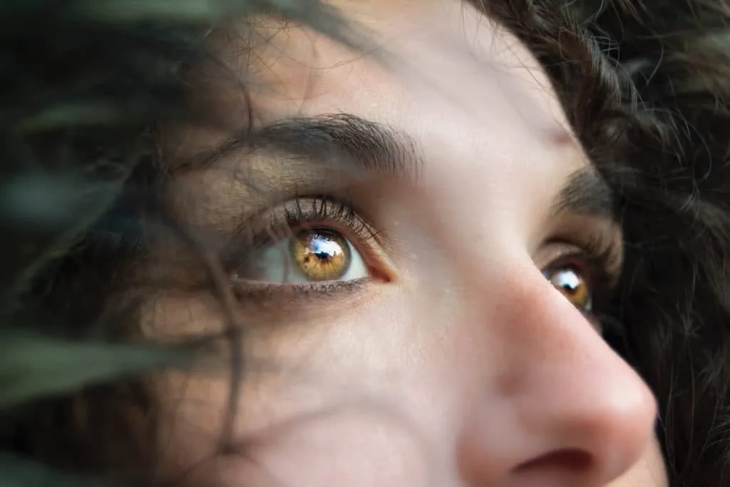 Close-up of a person's face showing golden-brown eyes with dark hair partially framing the face
